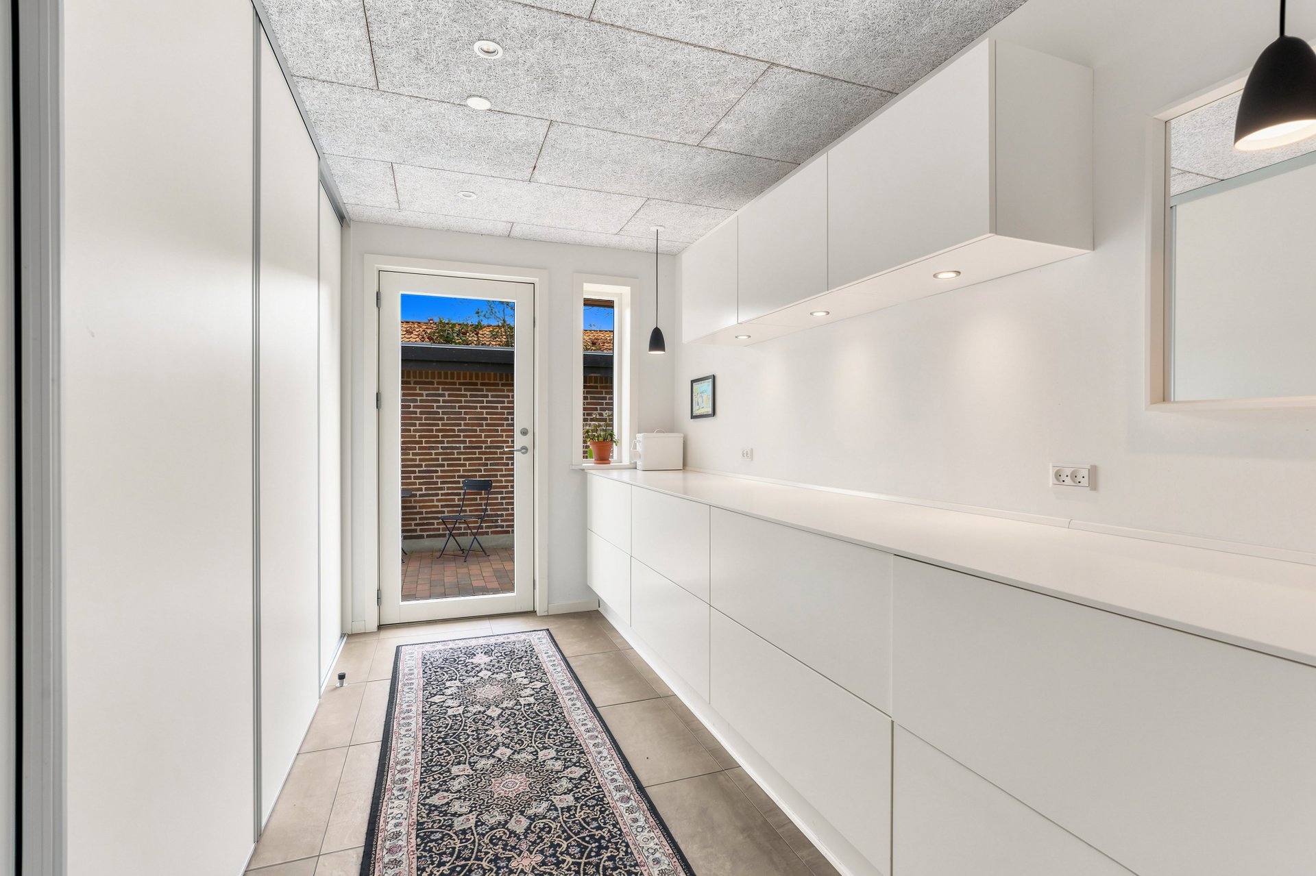 Bryggers med grebsfrie hvide skabe, klinkegulv og glasdør til gårdhaven – villa på Spurvevænget 47, Hjerting, 6710 Esbjerg V